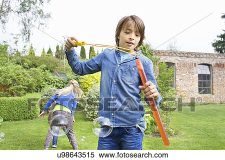SIblings playing with soap bubbles in garden View Large Photo Image Stock Photography - SIblings playing with soap bubbles in garden. Fotosearch