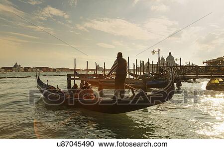 Stock Image - Silhouetted view of gondolier at sunset, Venice, Veneto, Italy. Fotosearch