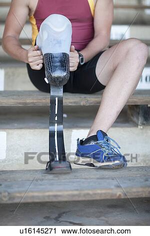 Stock Image - Sprinter preparing, putting on prosthetic leg. Fotosearch