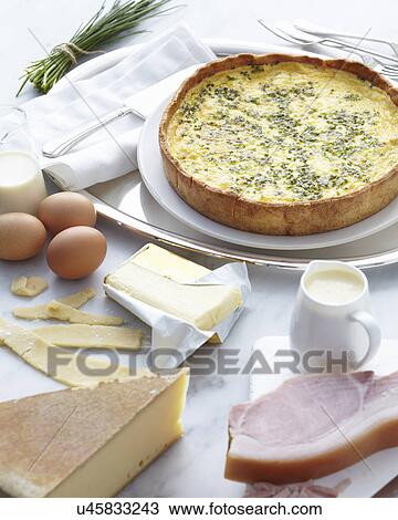 Stock Image - Still life of classic ready to eat quiche and the raw ingredients. Fotosearch