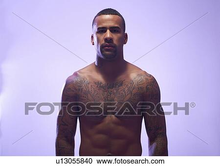 Stock Image - Studio portrait of muscular sportsman with bare chest and tattoos. Fotosearch