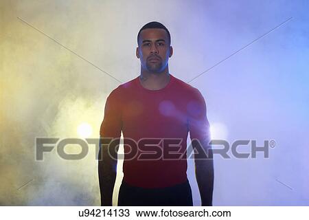 Stock Image - Studio portrait of muscular young sportsman in spotlights and mist. Fotosearch