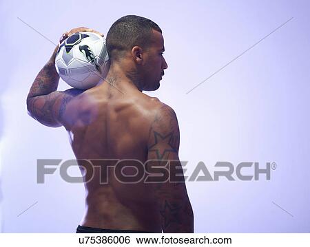 Studio shot of young male soccer player holding up ball on shoulder View Large Photo Image Stock Photograph - Studio shot of young male soccer player holding up ball on shoulder. Fotosearch