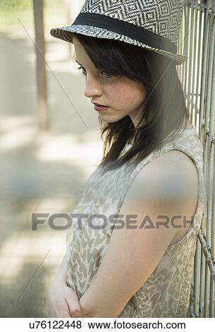 Stock Photo - Sullen young woman behind park fence. Fotosearch