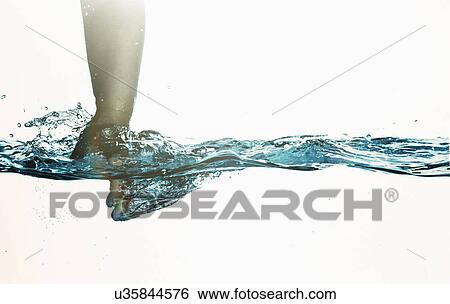 Stock Photograph - Surface level view of toddlers hand plunging into clear water. Fotosearch