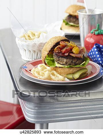 Stock Image - Table for two with cheeseburgers and onion rings. Fotosearch