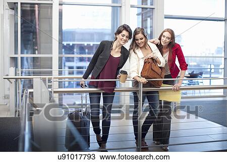 Stock Image - Three businesswomen watching from balcony in conference centre. Fotosearch