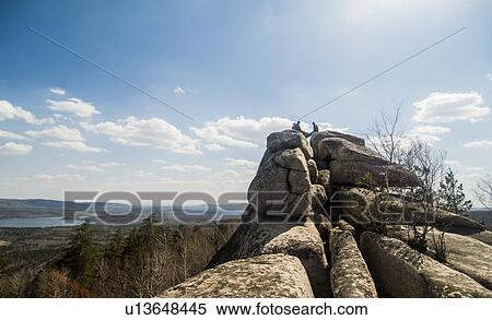 Three male hikers on top of rock formation with lake in distance View Large Photo Image Stock Photography - Three male hikers on top of rock formation with lake in distance. Fotosearch