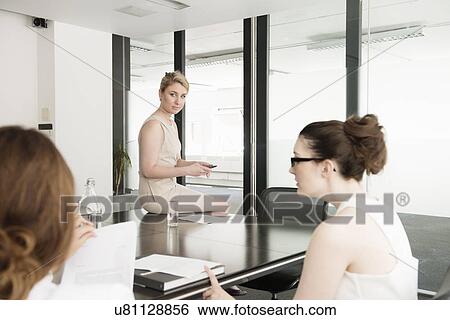 Stock Photograph - Three young businesswomen at meeting in conference room. Fotosearch