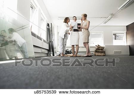 Three young businesswomen chatting in new office View Large Photo Image Stock Photo - Three young businesswomen chatting in new office. Fotosearch