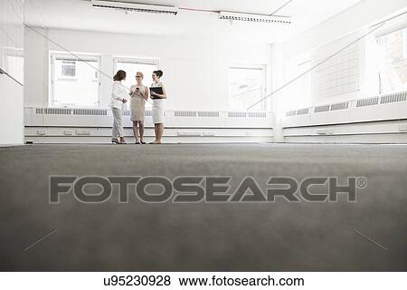 Stock Photo - Three young businesswomen planning in empty office. Fotosearch