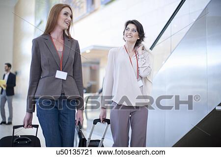 Stock Image - Two businesswoman arriving at conference centre. Fotosearch