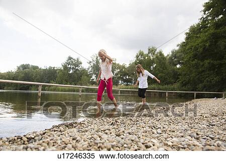 Stock Photography - Two girls paddling in rural lake. Fotosearch