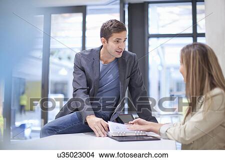 Two office workers in discussion View Large Photo Image Picture - Two office workers in discussion. Fotosearch