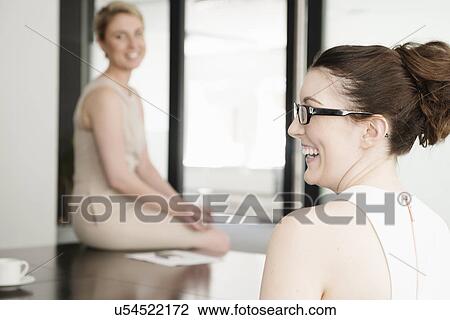 Stock Image - Two young businesswomen at meeting in conference room. Fotosearch