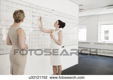 Two young businesswomen having planning meeting in office View Large Photo Image Stock Image - Two young businesswomen having planning meeting in office. Fotosearch