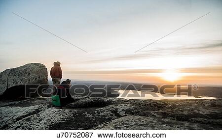 Two young female hikers gazing at sunset over distant lake View Large Photo Image Stock Photo - Two young female hikers gazing at sunset over distant lake. Fotosearch