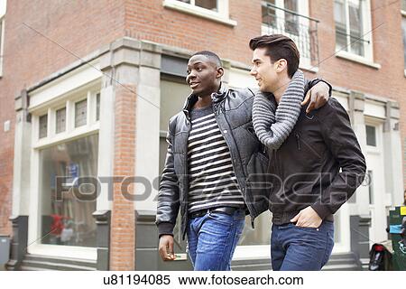 Two young men strolling down the street with arms around each other View Large Photo Image Stock Photography - Two young men strolling down the street with arms around each other. Fotosearch
