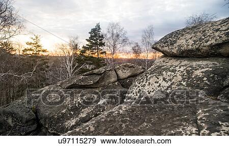 Stock Photo - View of boulders and tree tops at sunset. Fotosearch