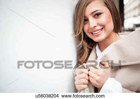 Picture - Woman leaning against white wall. Fotosearch