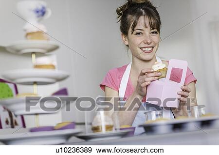 Stock Photo - Woman packing homemade cupcakes. Fotosearch