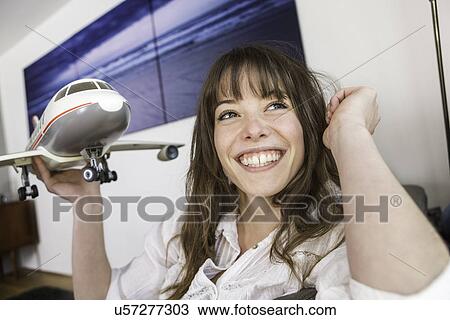 Stock Image - Woman playing with toy airplane. Fotosearch