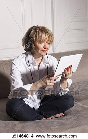 Picture - Woman using digital tablet on sofa. Fotosearch