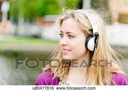 Stock Photograph - Woman with headphones by canal. Fotosearch