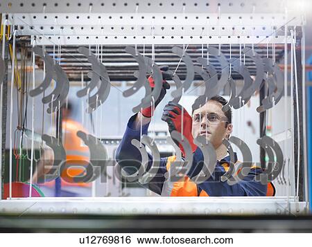 Worker arranging metal parts for paint spraying in sheet metal factory View Large Photo Image Stock Photograph - Worker arranging metal parts for paint spraying in sheet metal factory. Fotosearch