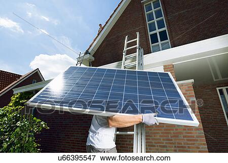 Worker climbing ladder carrying solar panel for roof of new home, Netherlands View Large Photo Image Stock Photo - Worker climbing ladder carrying solar panel for roof of new home, Netherlands. Fotosearch