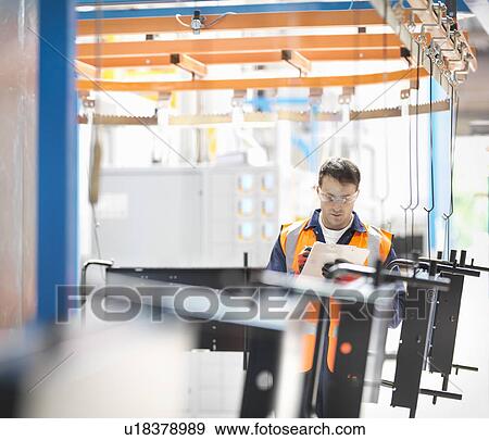 Stock Photo - Worker inspecting painted parts in sheet metal factory. Fotosearch