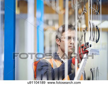Stock Photo - Worker inspecting painted parts in sheet metal factory. Fotosearch