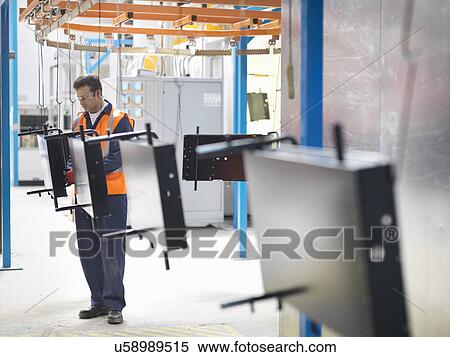 Stock Photography - Worker inspecting painted parts in sheet metal factory. Fotosearch