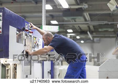 Stock Image - Worker using machine in paper packaging factory. Fotosearch