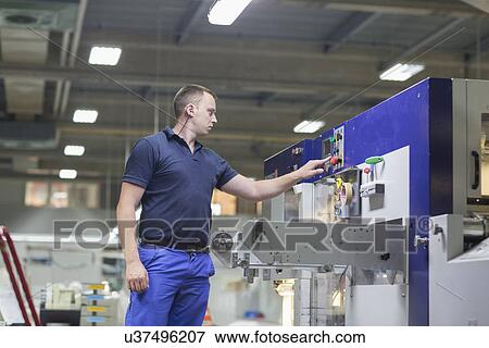 Stock Photo - Worker using machine in paper packaging factory. Fotosearch