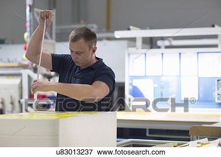 Stock Photo - Worker using machine in paper packaging factory. Fotosearch