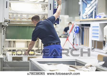 Stock Photography - Worker using machine in paper packaging factory. Fotosearch