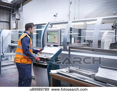 Stock Photo - Worker using robotic metal cutting machine in sheet metal factory. Fotosearch