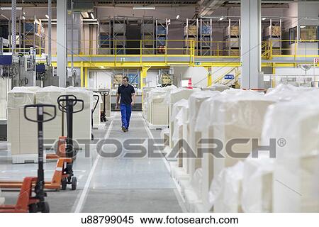 Stock Photography - Worker walking through paper packaging factory. Fotosearch