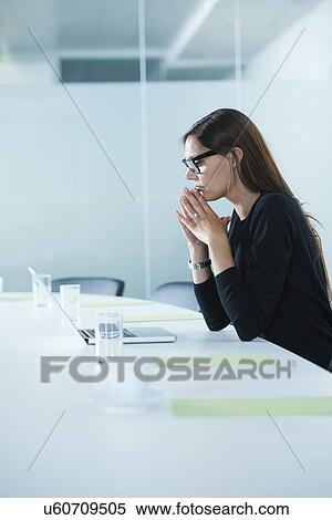 Worried female office worker using laptop at conference table View Large Photo Image Stock Photography - Worried female office worker using laptop at conference table. Fotosearch