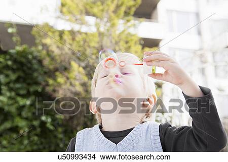 Picture - Young boy blowing bubbles in garden. Fotosearch
