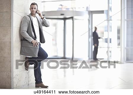 Young businessman chatting on smartphone in conference centre atrium View Large Photo Image Stock Image - Young businessman chatting on smartphone in conference centre atrium. Fotosearch
