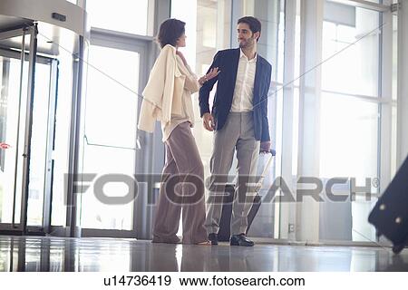 Stock Photo - Young businesswoman and businessman arriving at conference centre. Fotosearch