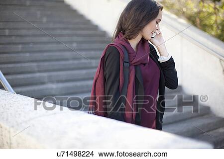 Picture - Young businesswoman chatting on smartphone on city stairway. Fotosearch