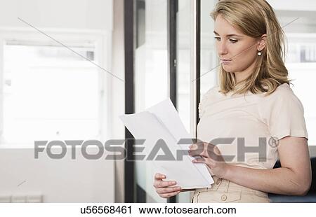 Stock Image - Young businesswoman checking paperwork. Fotosearch