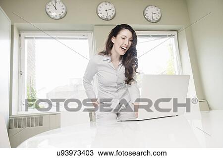 Young businesswoman laughing at laptop View Large Photo Image Stock Image - Young businesswoman laughing at laptop. Fotosearch