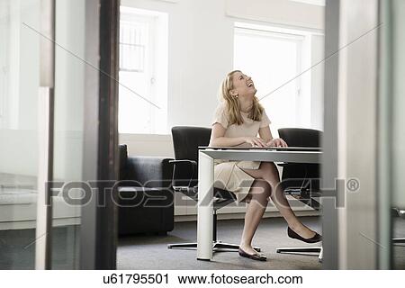 Stock Image - Young businesswoman laughing in boardroom. Fotosearch