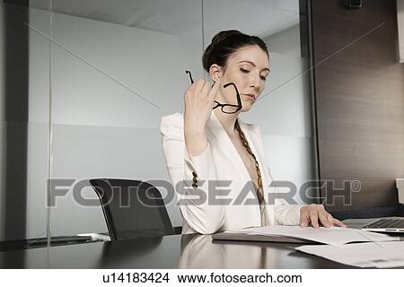 Young businesswoman reading paperwork in office View Large Photo Image Picture - Young businesswoman reading paperwork in office. Fotosearch