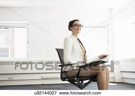 Stock Photo - Young businesswoman sitting in new office. Fotosearch