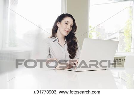 Young businesswoman using laptop in office View Large Photo Image Stock Image - Young businesswoman using laptop in office. Fotosearch